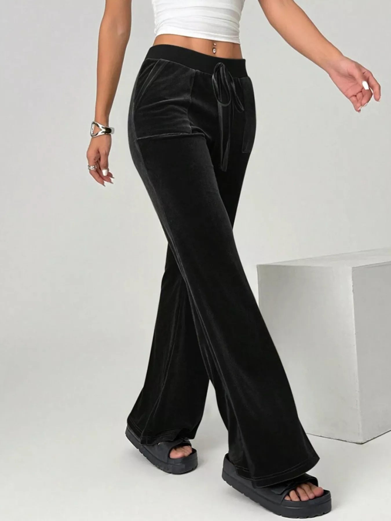 Black velvet pants worn by a person on a white background