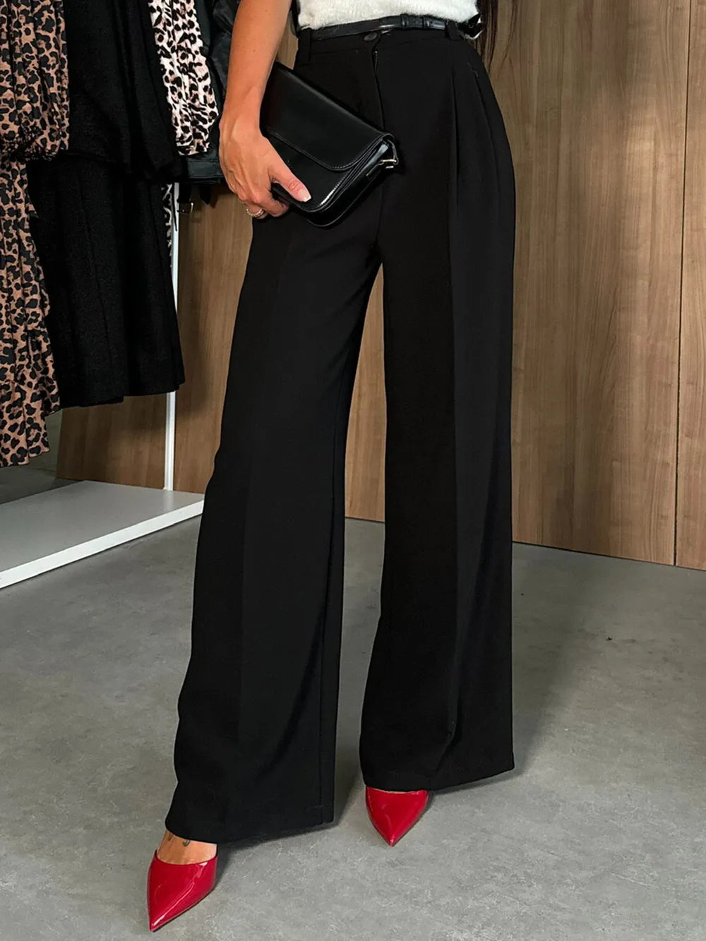 Person wearing black wide-leg pants with red shoes in a room setting.