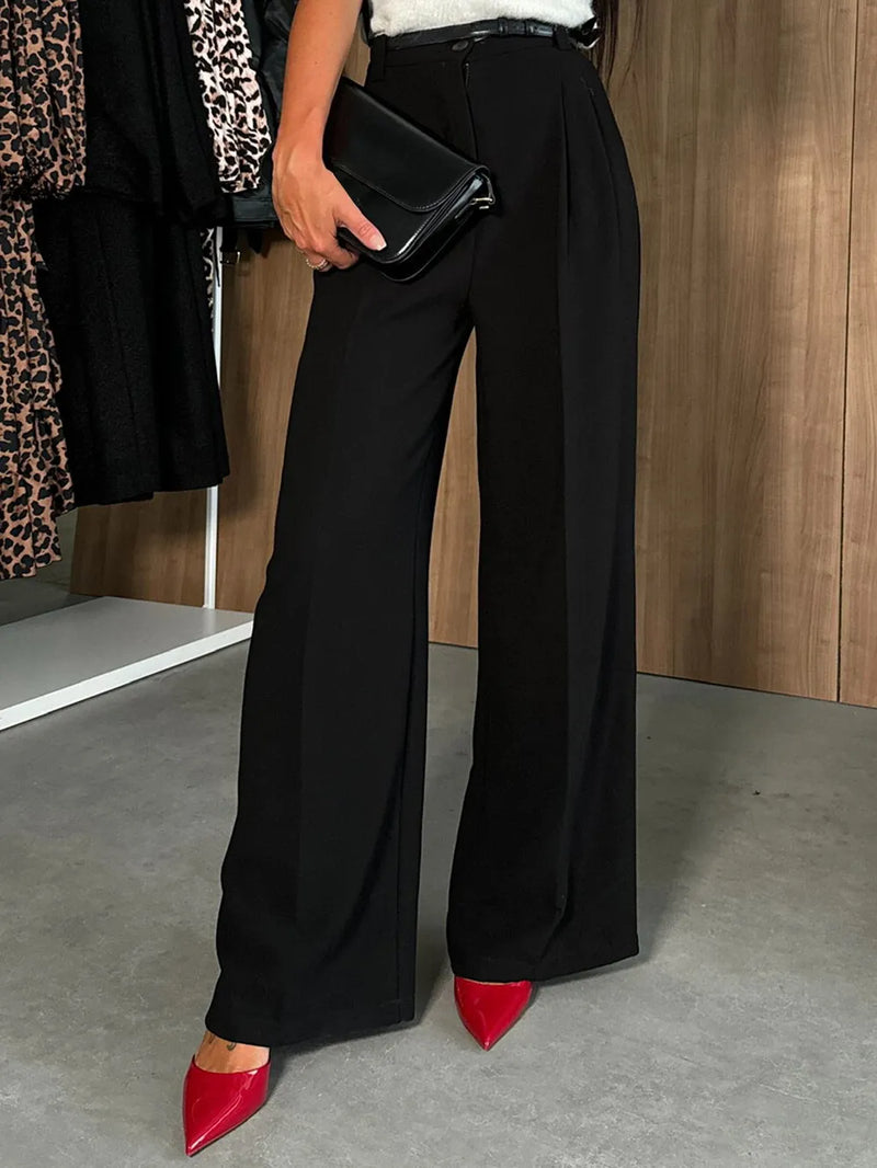 Person wearing black wide-leg pants with red shoes in a room setting.