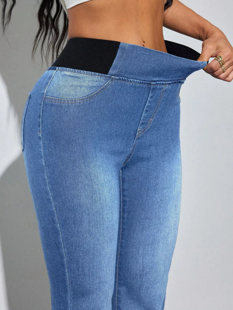 Close-up of blue jeans being adjusted on a person against a gray background