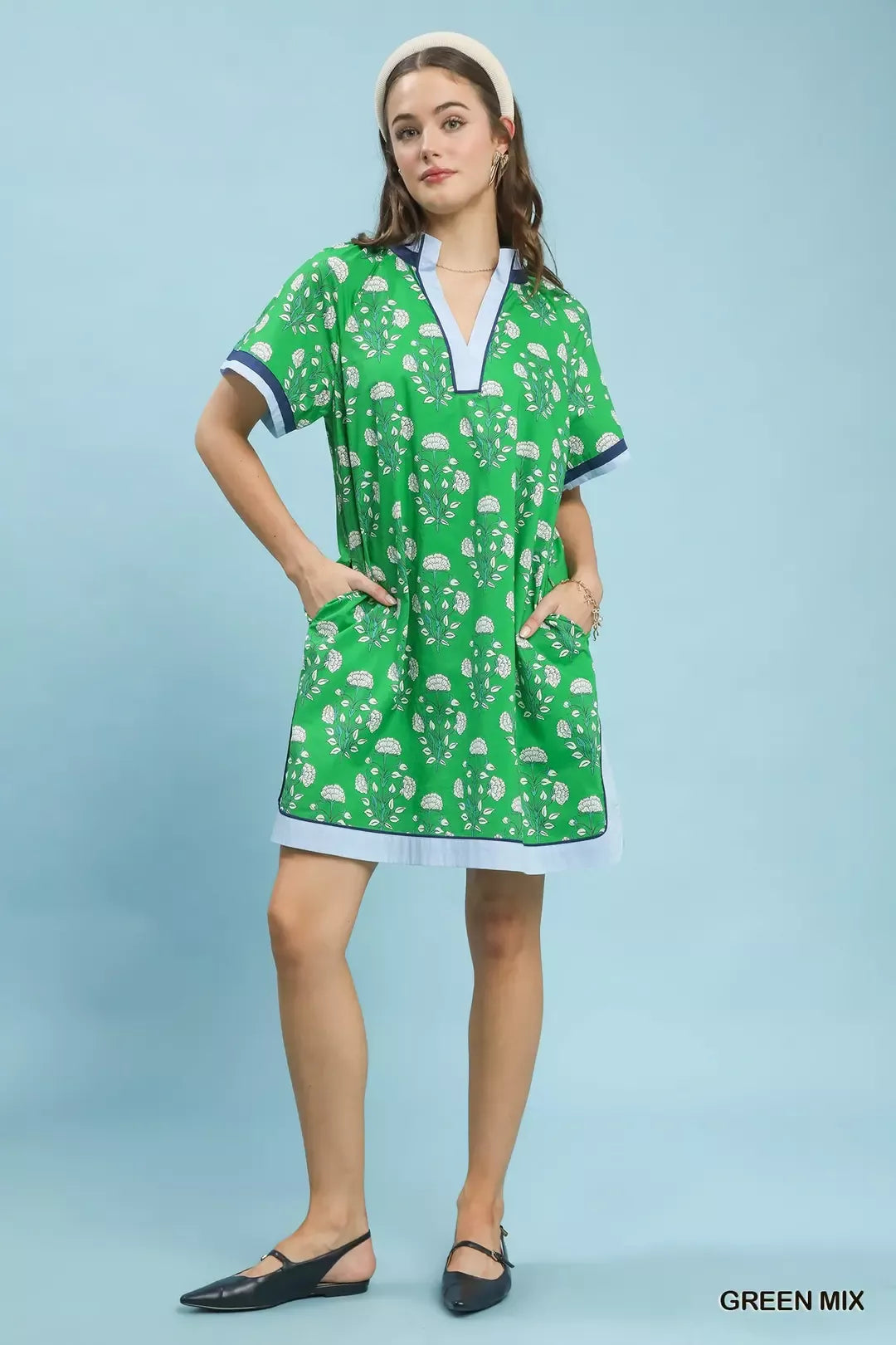 Woman wearing a green patterned dress on a light blue background