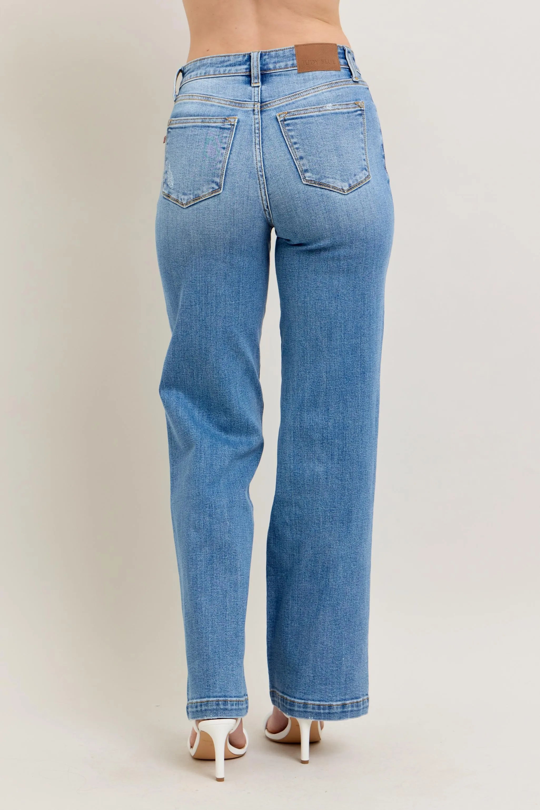 Blue jeans worn by a person on a plain background