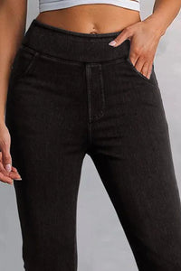 Person wearing black high-waisted jeans on a gray background