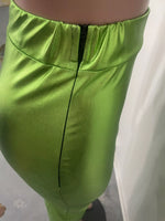 Close-up of green satin pants with a plain background