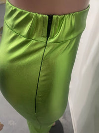 Close-up of green satin pants with a plain background