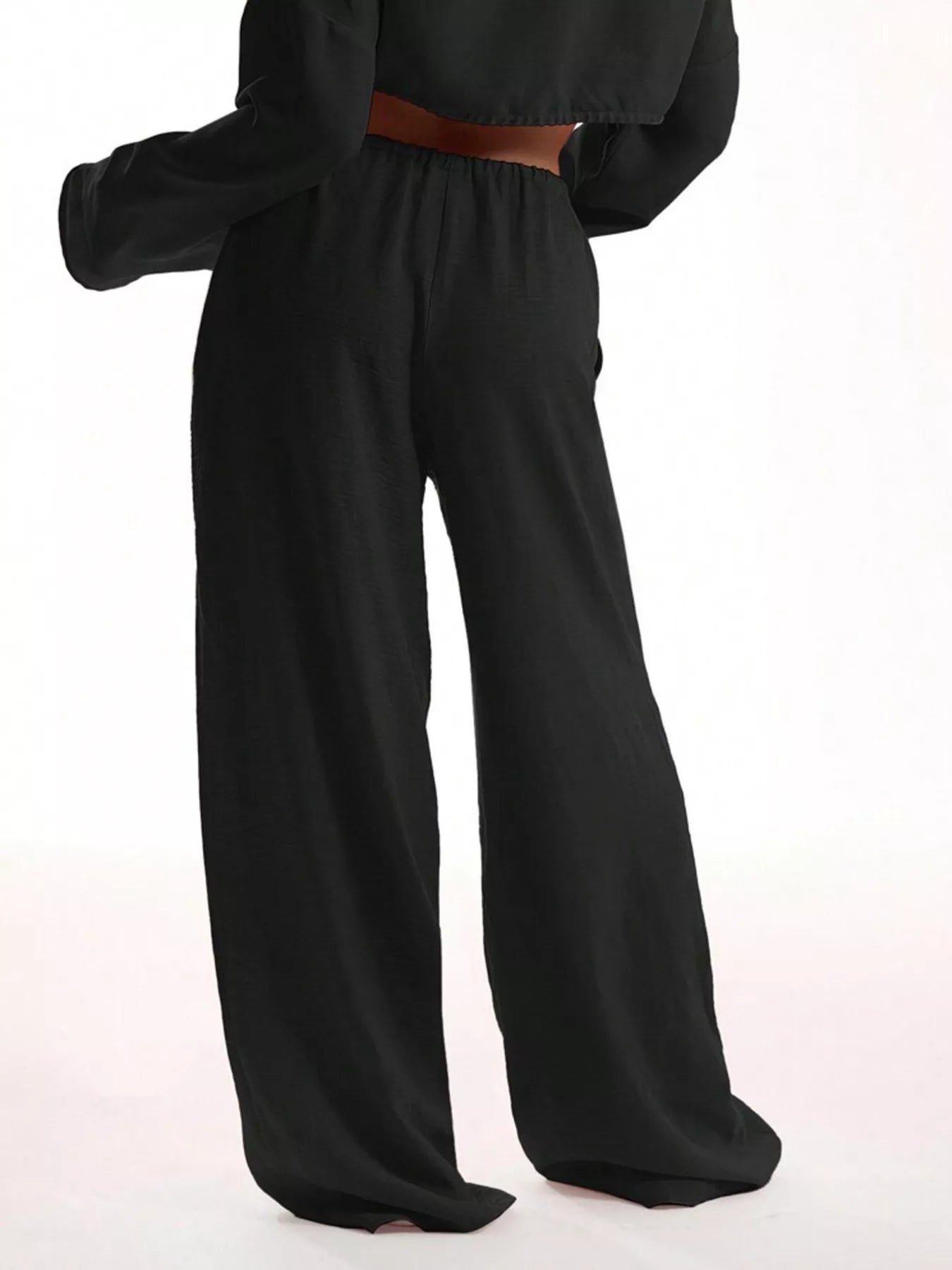 Black wide-leg pants with a brown belt on a white background