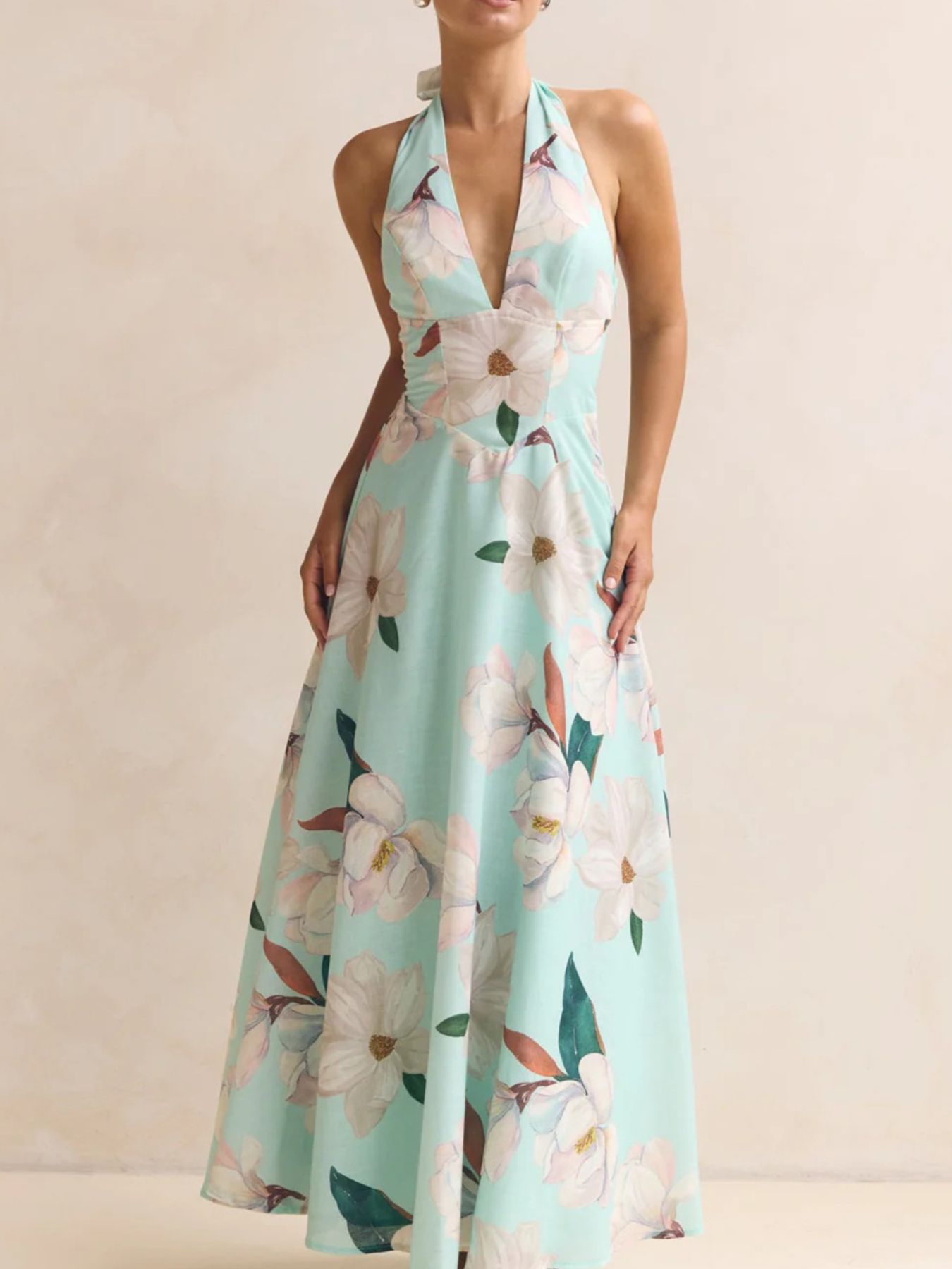 Woman wearing a floral halter neck dress on a beige background