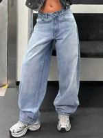 Person wearing light blue jeans and white sneakers in an indoor setting