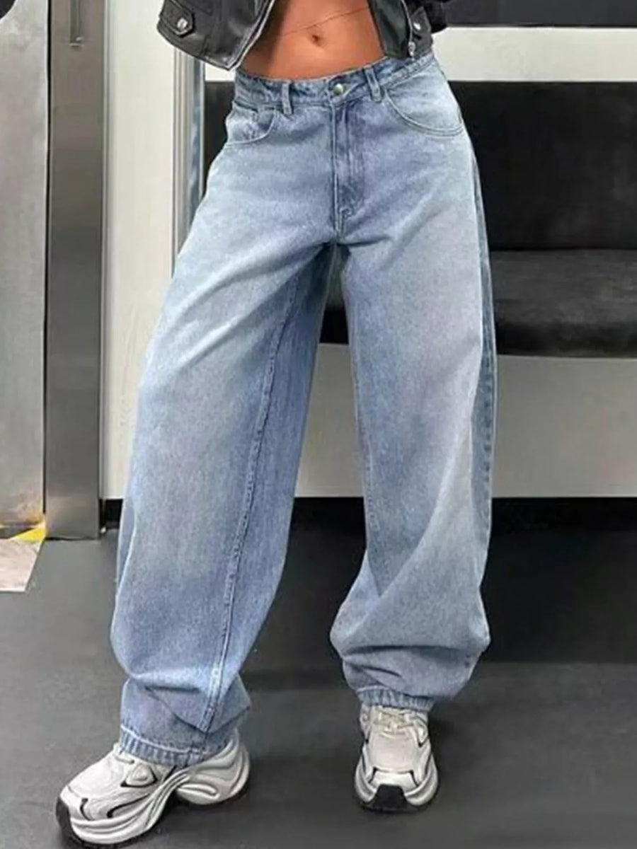 Person wearing light blue jeans and white sneakers in an indoor setting
