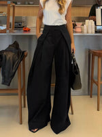 Person wearing a white top and black wide-leg pants in a kitchen setting.