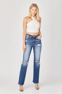 Woman wearing a white halter top and distressed blue jeans on a white background