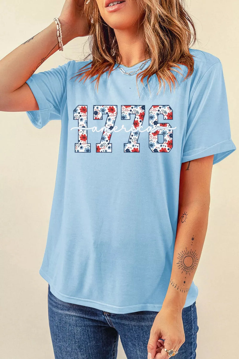 Woman wearing a light blue t-shirt with '1776' printed on it against a beige background
