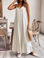Woman in a white dress holding a straw bag in a room with wooden furniture.