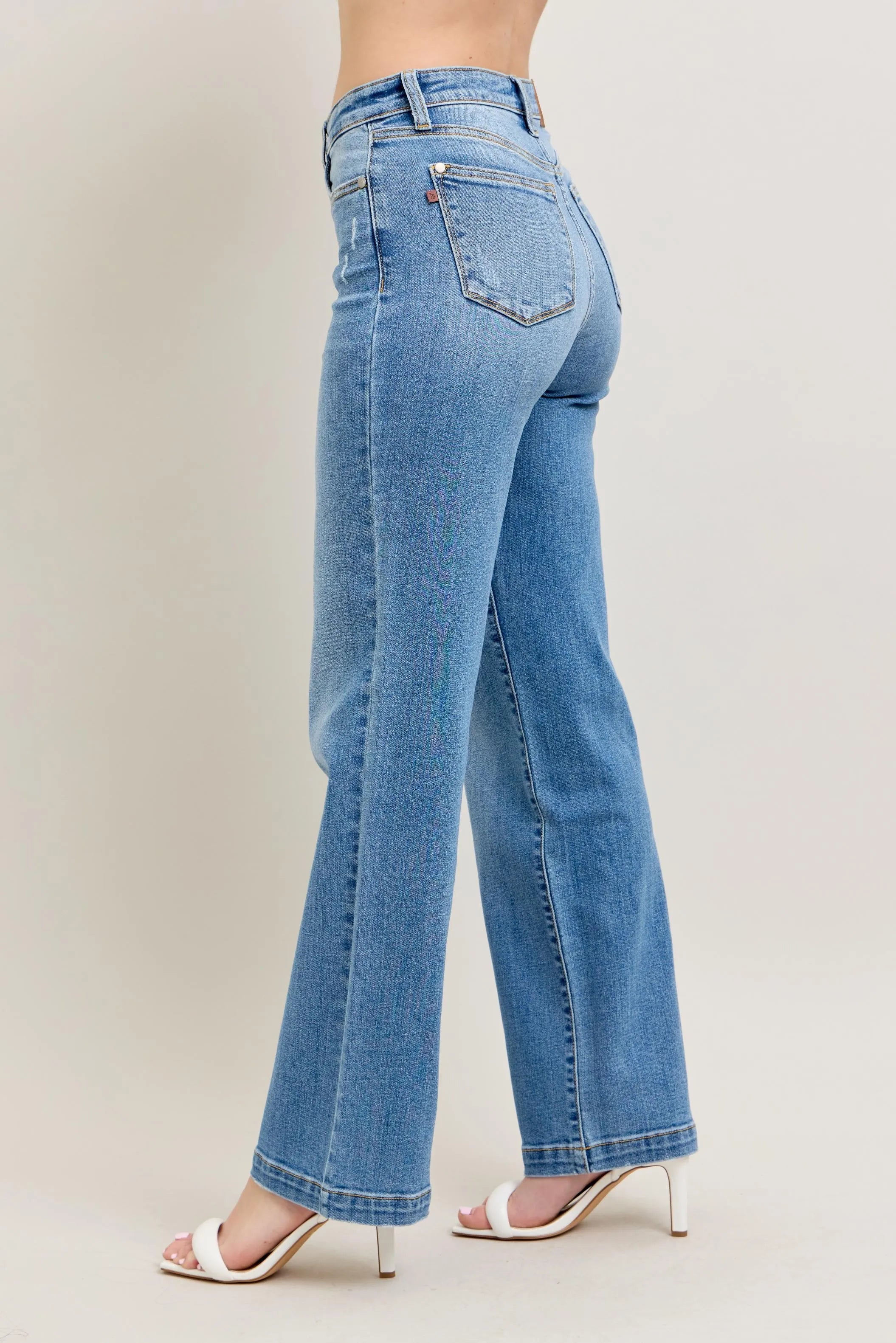 Blue jeans worn by a person on a plain background