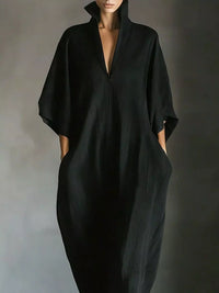 Person wearing a black dress against a gray background