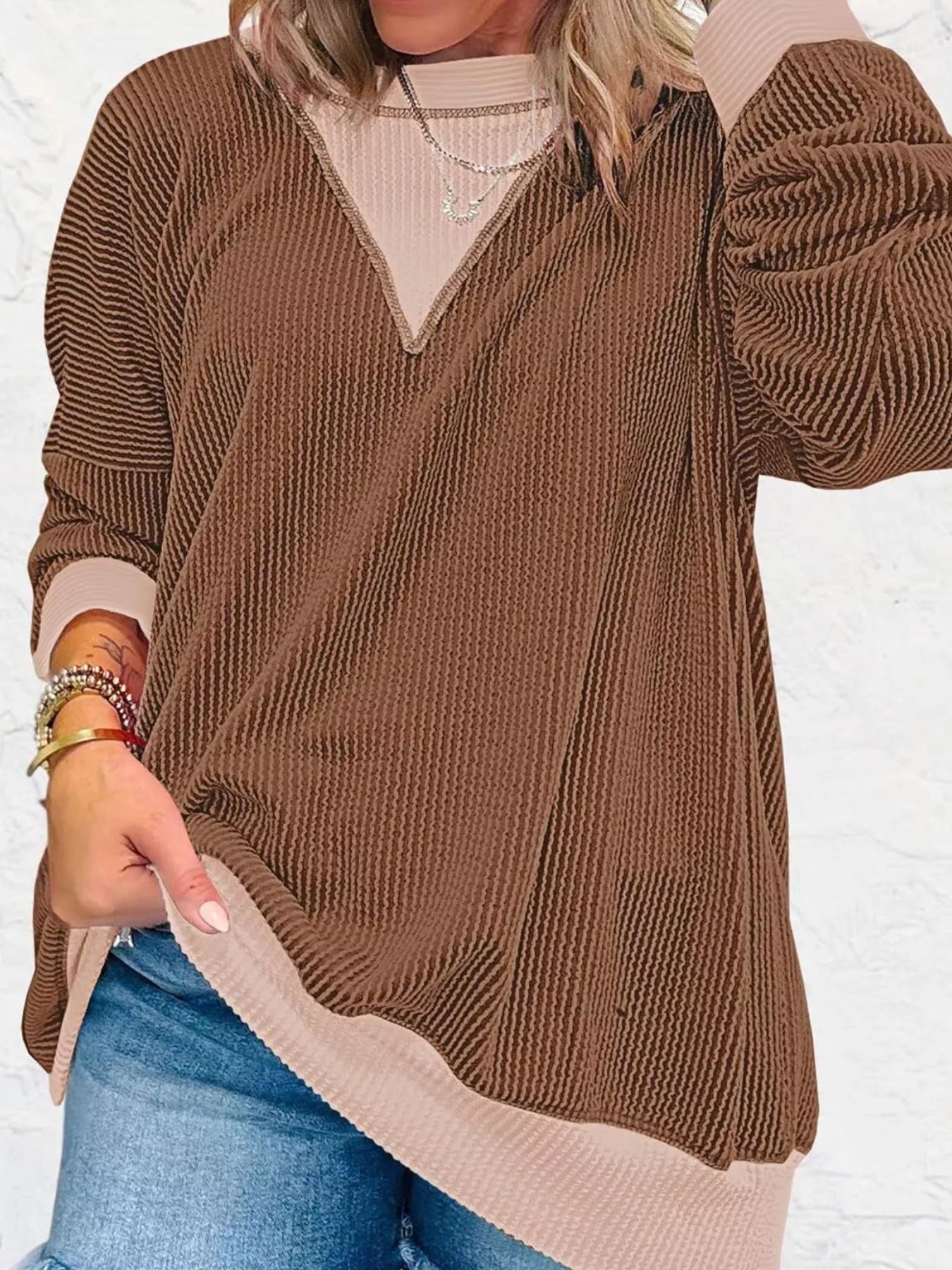 Brown sweater with beige collar and cuffs worn by a person on a white background