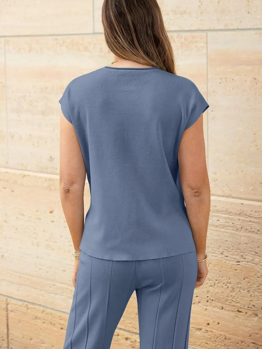 Woman wearing a blue outfit against a beige stone wall