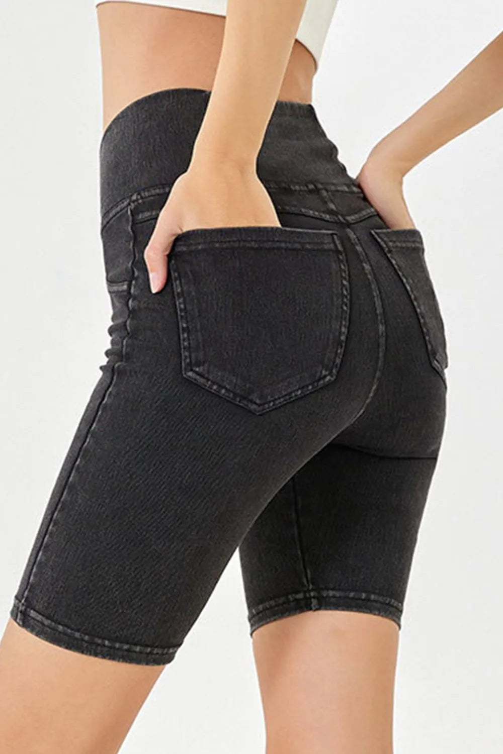 Black denim shorts worn by a person on a white background