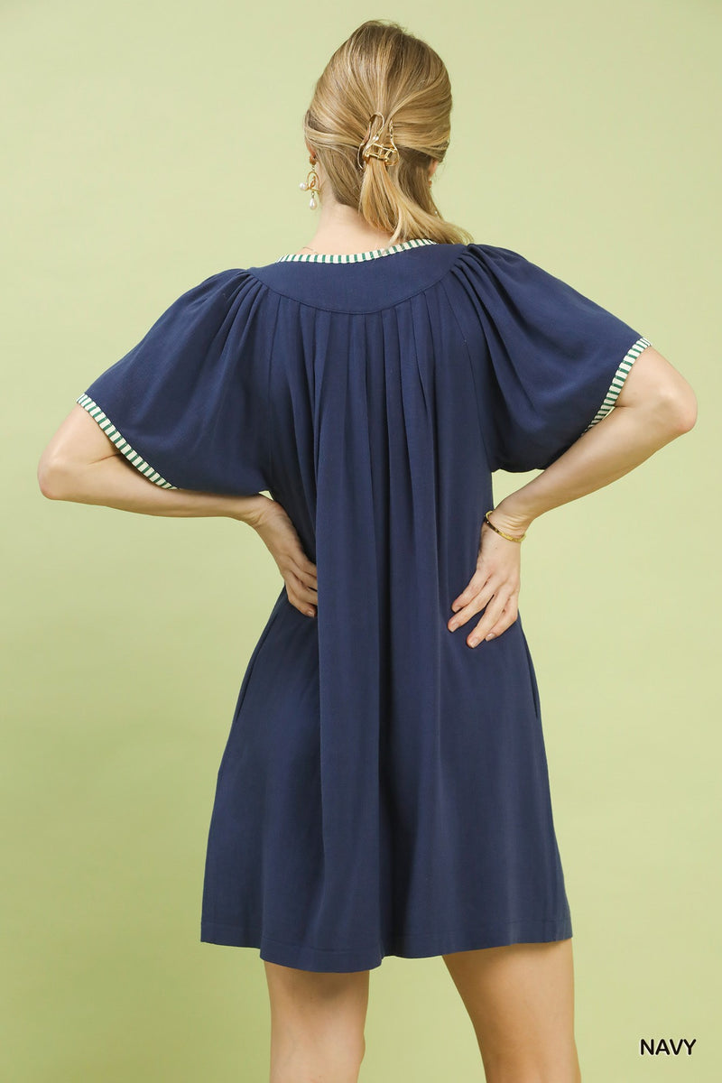 Navy dress with white trim on a green background
