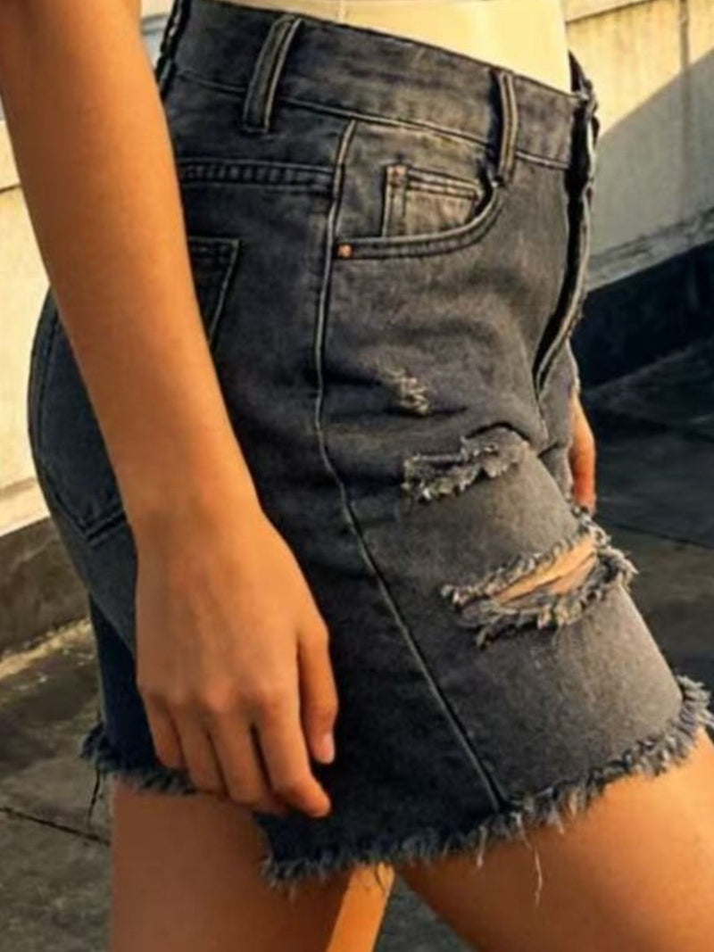 Person wearing a distressed denim skirt with a blurred background
