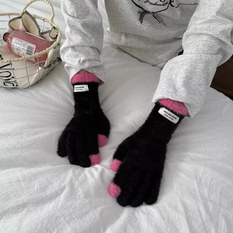 Person wearing black gloves with pink tips on a white surface