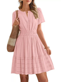 Woman wearing a pink dress holding a brown bag on a white background