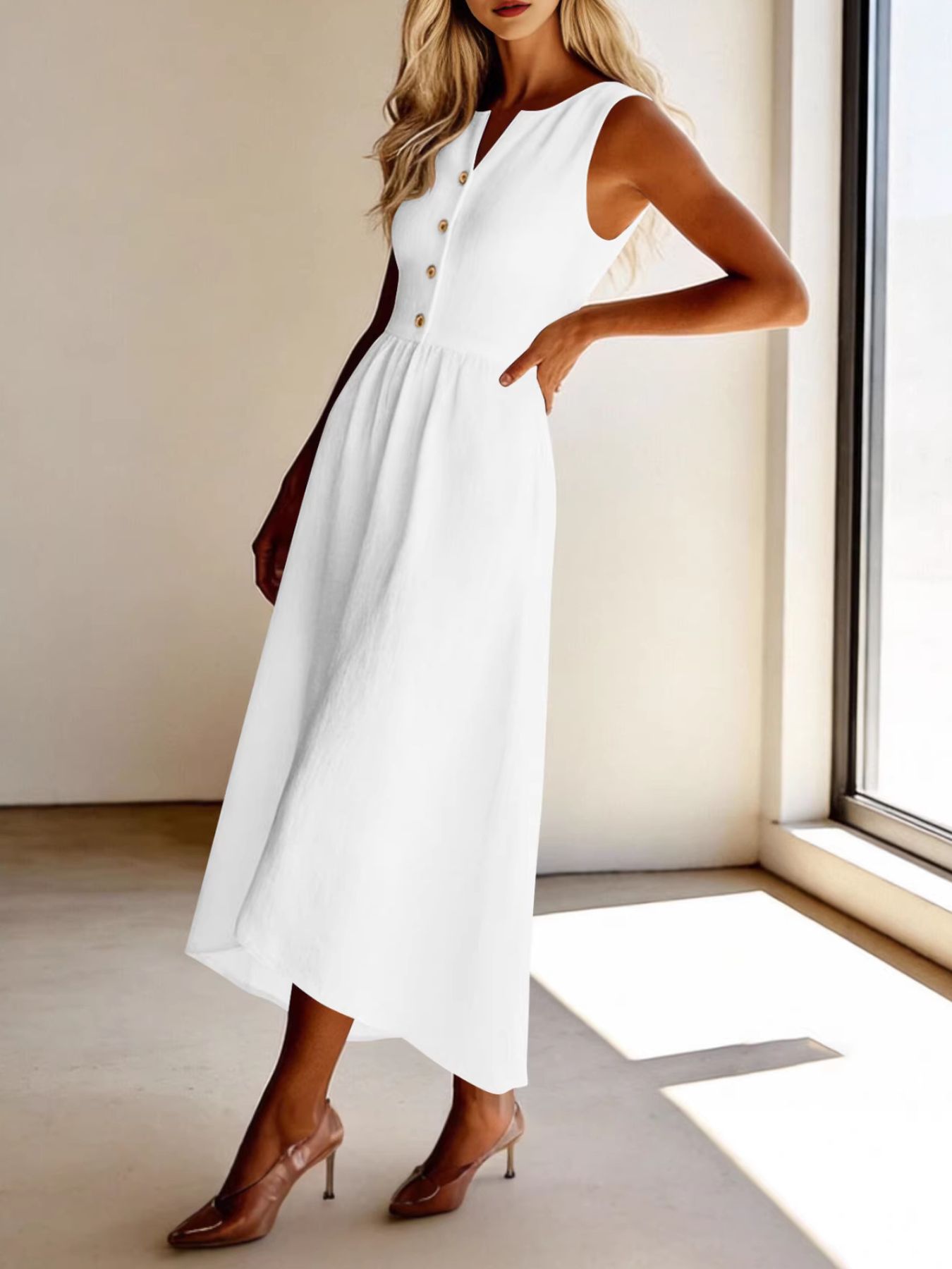 Woman wearing a white dress with gold buttons in a minimalistic room.