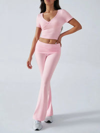Person wearing a pink outfit with a top and flared pants on a white background