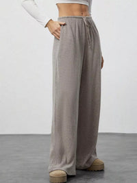 Person wearing gray wide-leg pants on a plain background