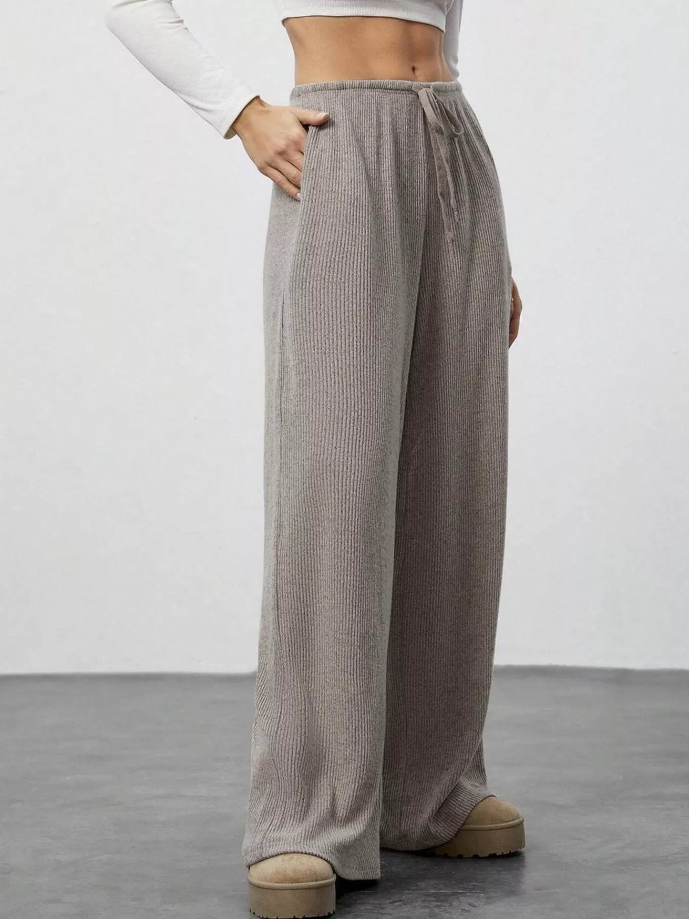 Person wearing gray wide-leg pants on a plain background