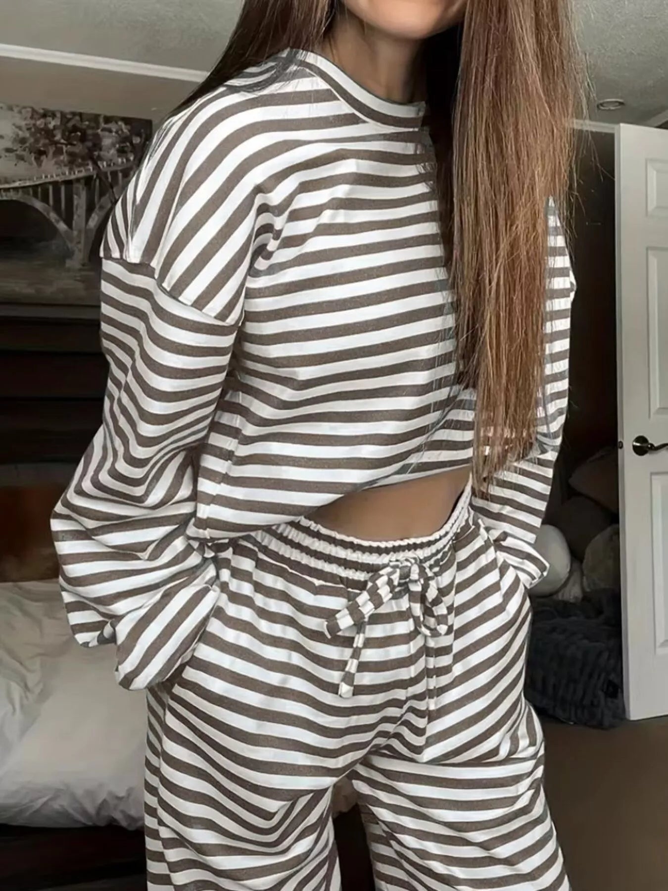 Person wearing a striped pajama set in a bedroom setting