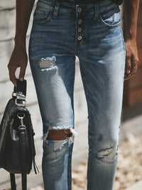 Ripped blue jeans worn by a person with a blurred background