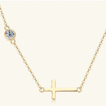 Gold necklace with a small round gemstone and a horizontal cross pendant on a white background