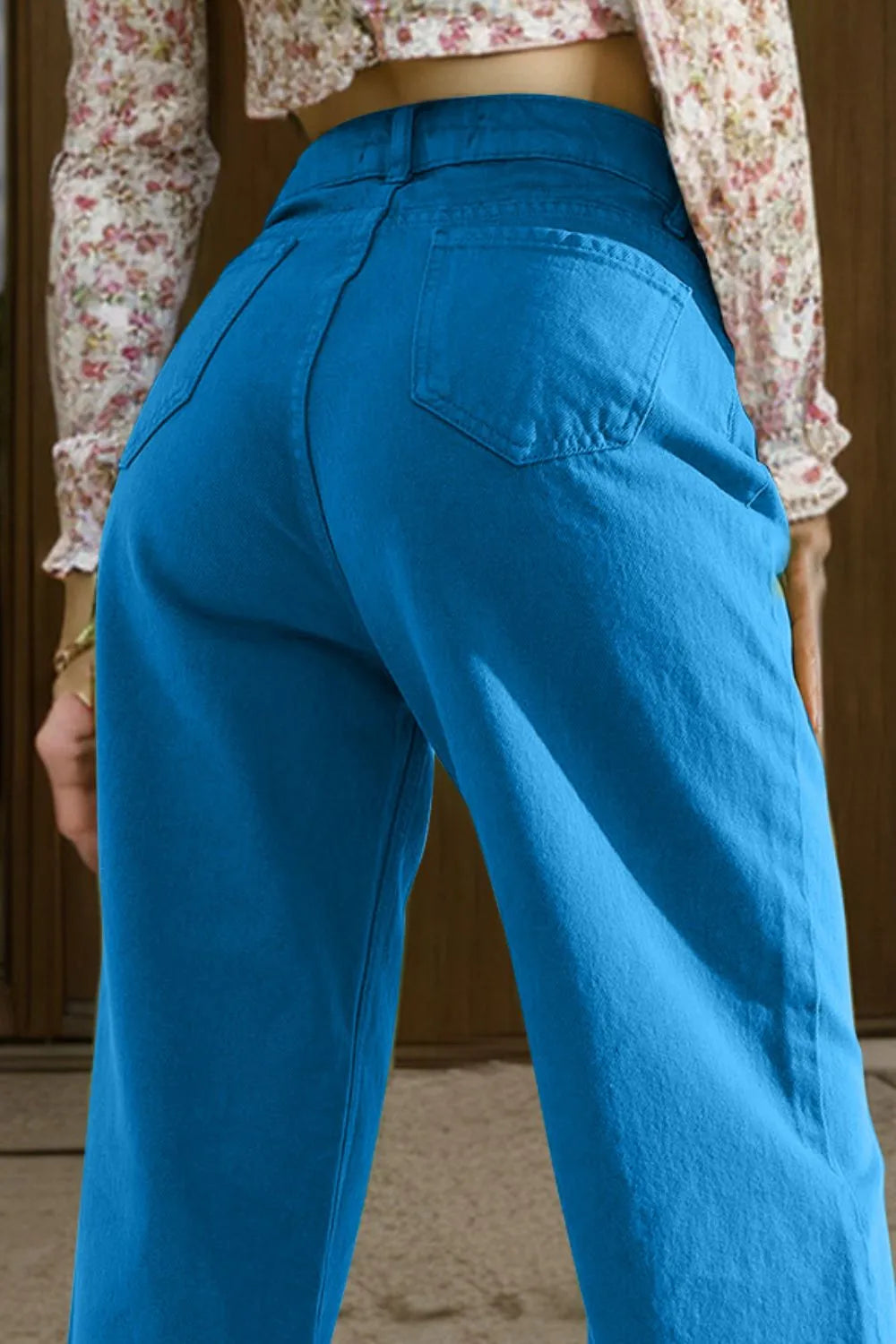 Person wearing blue pants with a floral top in the background