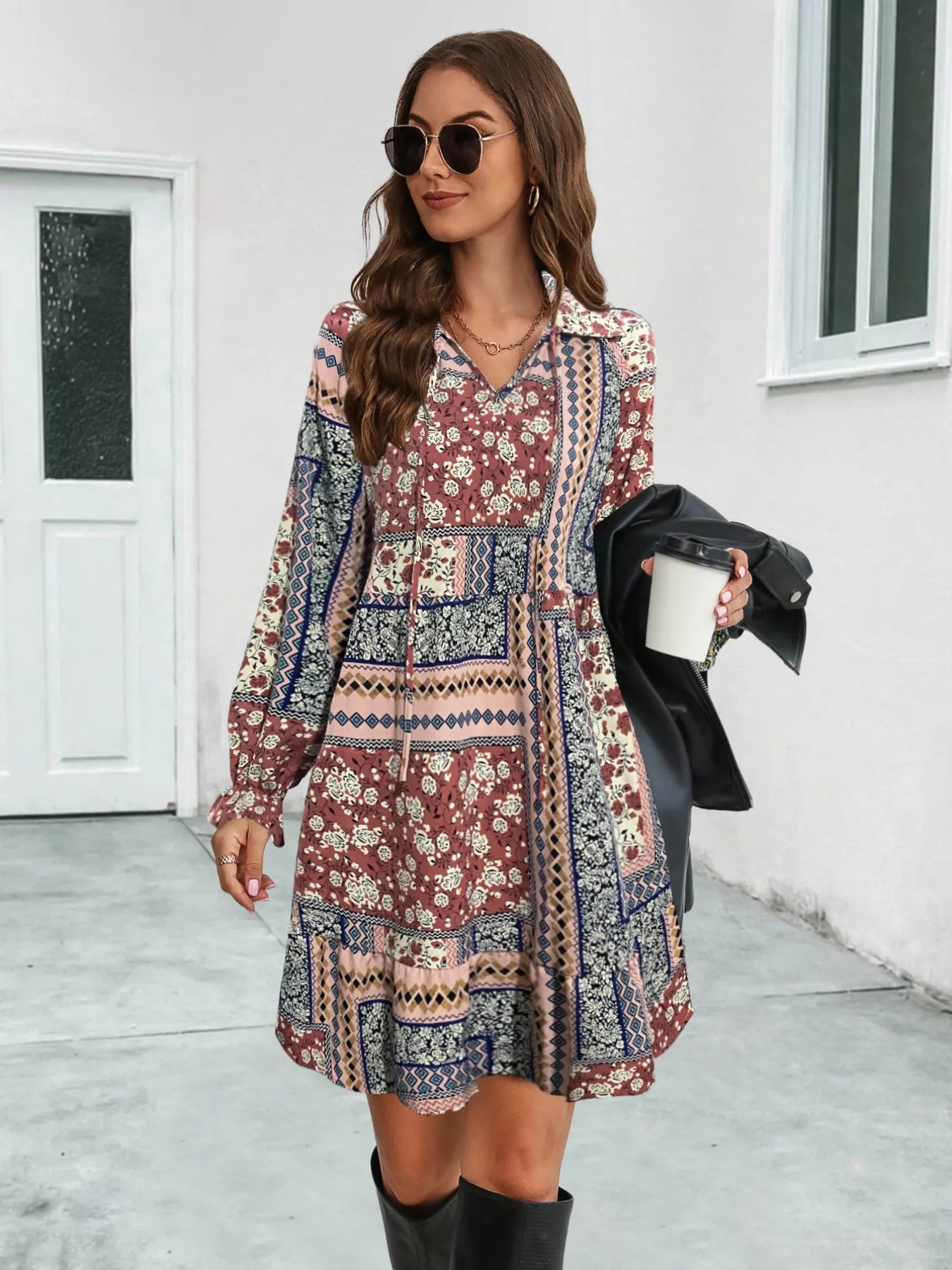 Woman wearing a patterned dress holding a coffee cup outdoors.