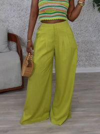 Person wearing a colorful cropped top and bright green wide-leg pants indoors.