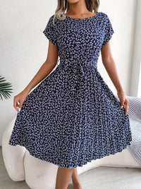 Woman wearing a navy blue floral dress in a minimal indoor setting