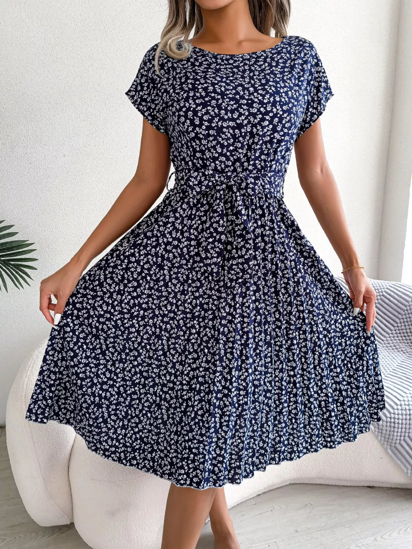 Woman wearing a navy blue floral dress in a minimal indoor setting