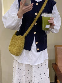 Person holding a green drink and a yellow bag, wearing a navy vest over a white shirt with polka dot pants.