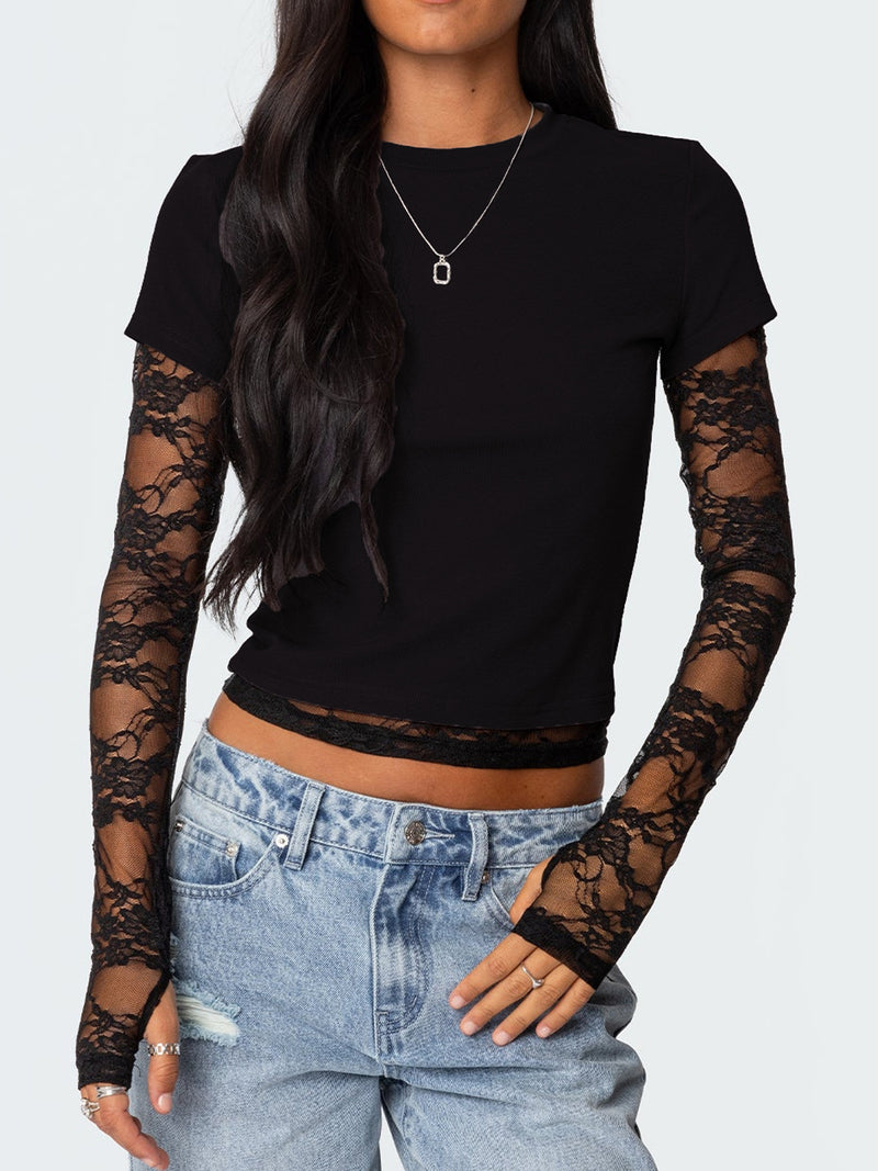 Person wearing a black long-sleeve top with lace sleeves and blue jeans on a white background