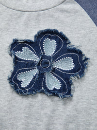Navy blue denim flower patch on a gray fabric background