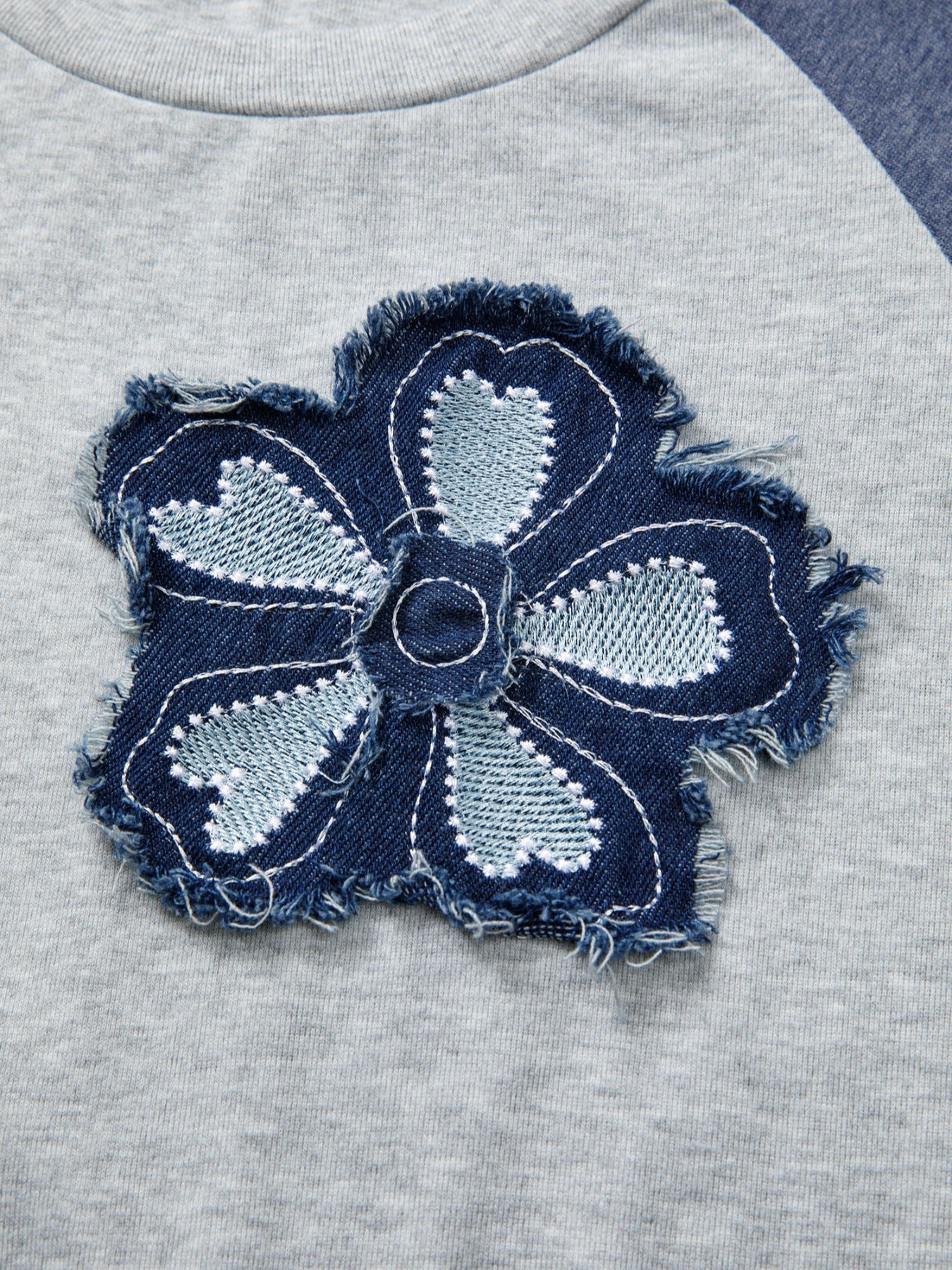 Navy blue denim flower patch on a gray fabric background