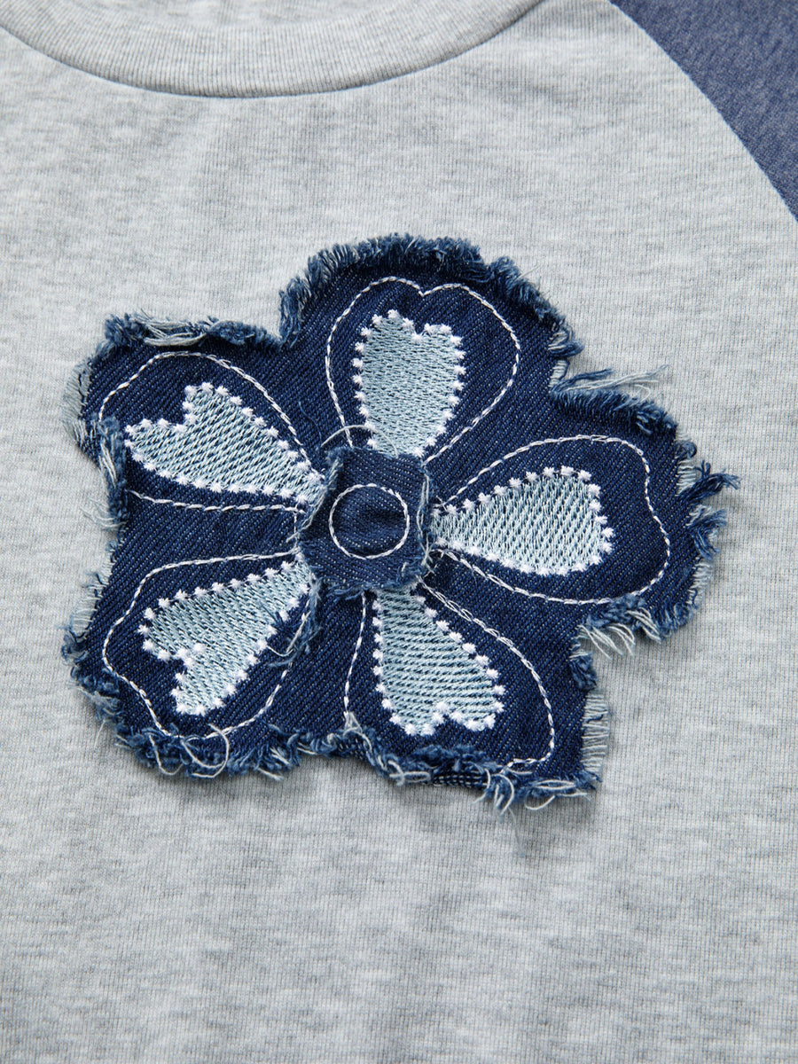 Navy blue denim flower patch on a gray fabric background