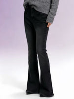 Person wearing black flared jeans and a gray sweater on a white background