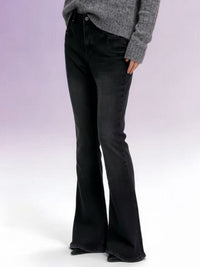 Person wearing black flared jeans and a gray sweater on a white background