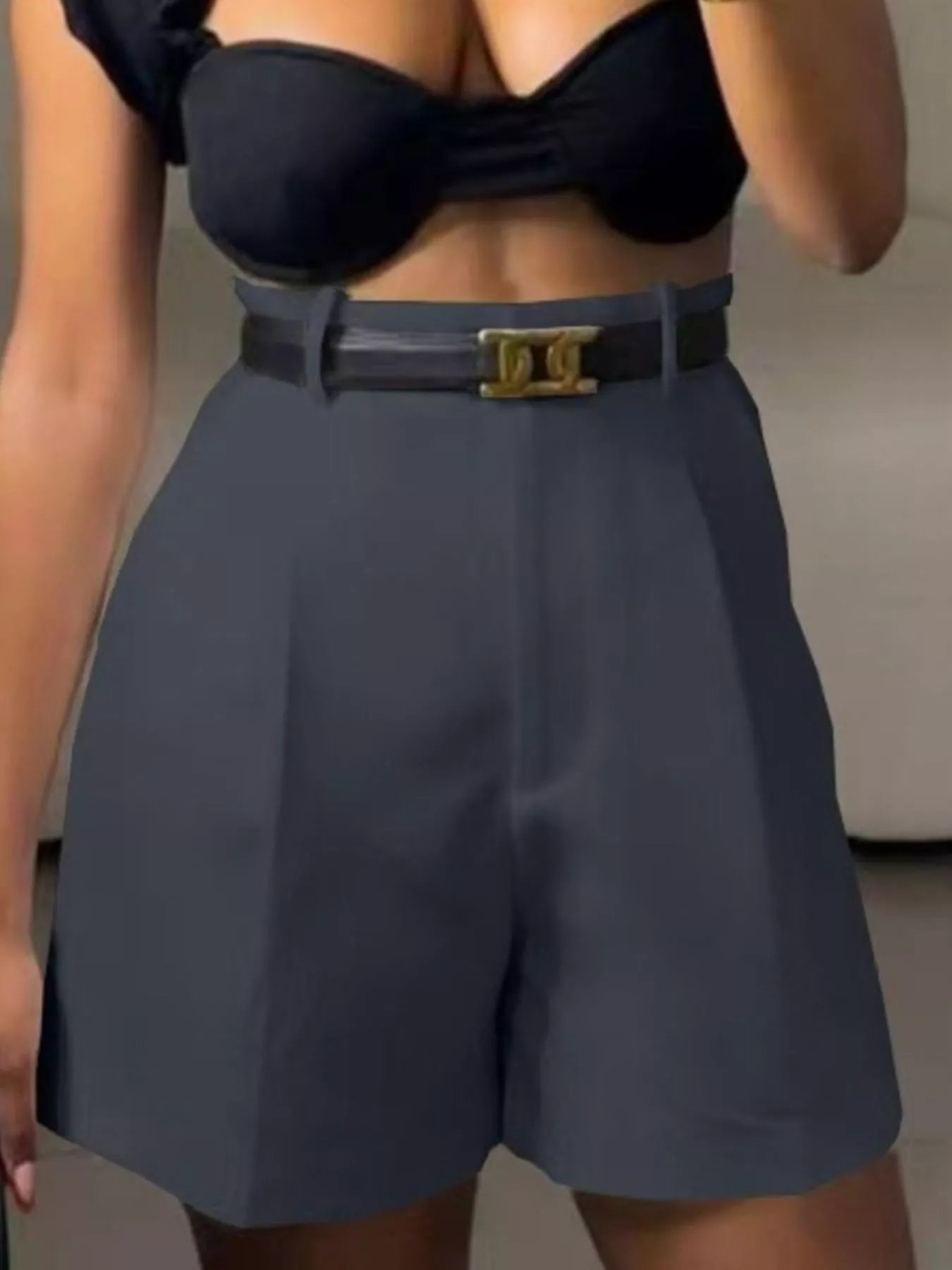 Person wearing a black strapless top and gray shorts with a belt.