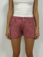 Person wearing pink shorts and a white top on a plain background