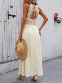 Woman in a white dress holding a straw hat against a white wall.