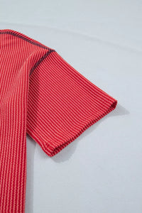 Red ribbed sweater sleeve on a light gray background