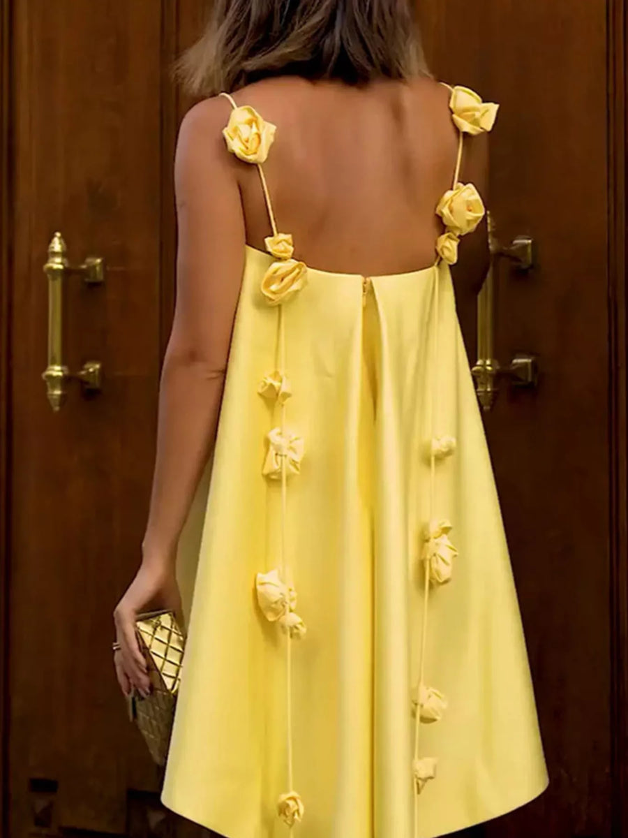 Yellow dress with floral details on straps against a wooden door background